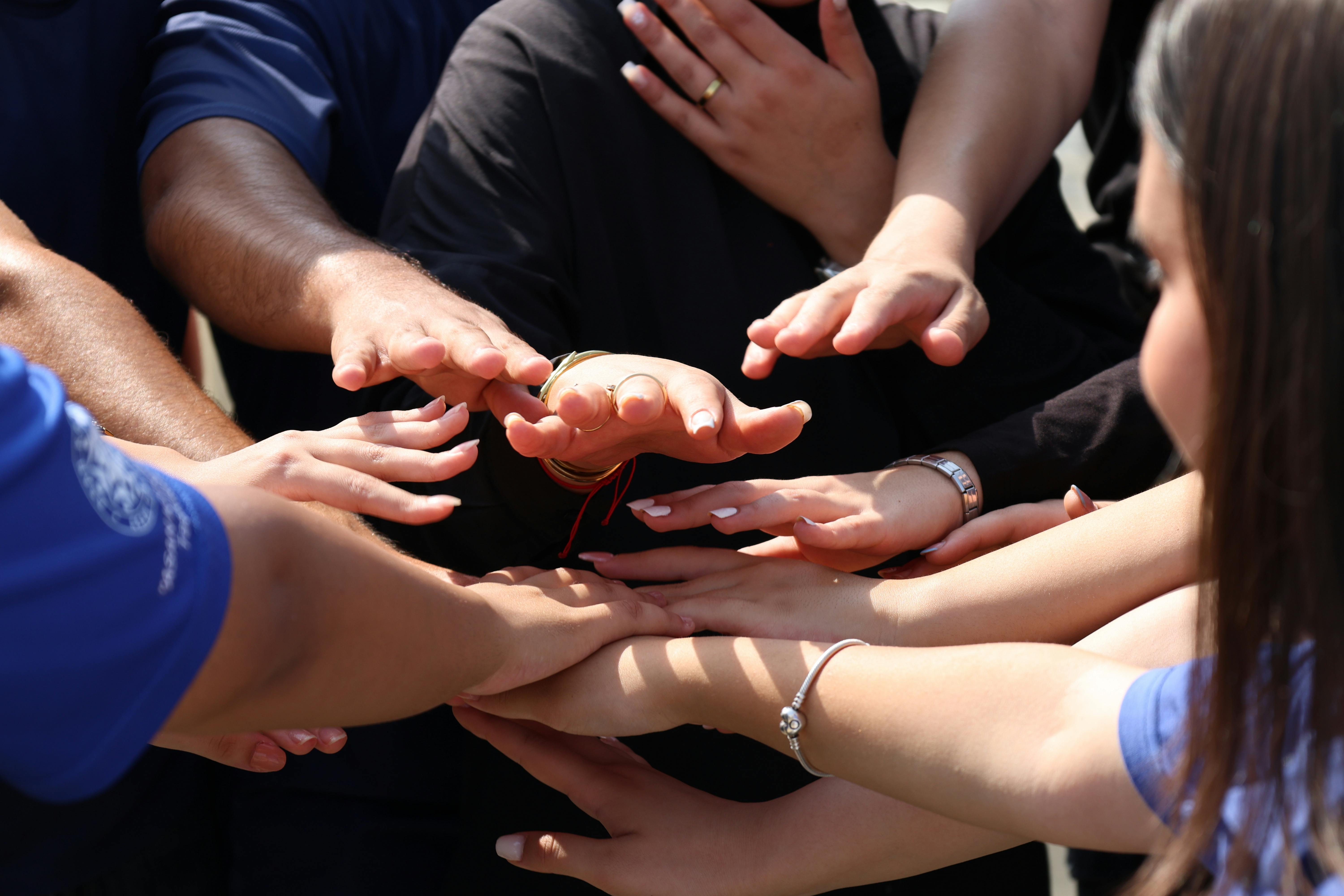 Group of people stacking hands together representing unity and community support